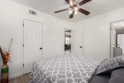 Relax in the spacious primary bedroom featuring updated flooring, ceiling fan, large windows, and direct bathroom access. A peaceful retreat that complements the updated interior of this Mesa home.