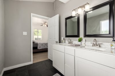 Stylish primary bathroom featuring dual sinks, updated cabinetry, modern mirrors, and ample storage. A thoughtfully updated space that enhances this move-in-ready Mesa home.