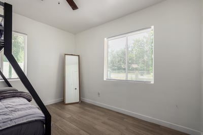 Bright guest bedroom with updated flooring, ceiling fan, and oversized windows providing excellent natural light. A flexible space ideal for guests, family, or a home office.