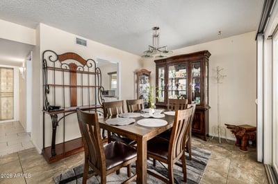 Spacious dining room featuring updated lighting, tile flooring, and sliding glass doors that open to the covered patio for convenient entertaining and outdoor enjoyment.