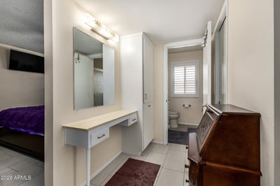 Functional dressing area with built-in vanity, additional storage cabinets, tile flooring, and easy access to the updated bathroom, creating a practical everyday space.