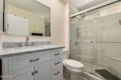Stylish bathroom showcasing a walk-in glass shower, marble-look countertop, updated vanity cabinetry, and contemporary fixtures designed for comfort and convenience.