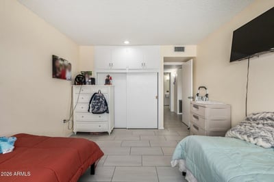 Another view of the guest bedroom highlighting abundant closet storage, durable tile flooring, and versatile space suited for visitors or a home office.