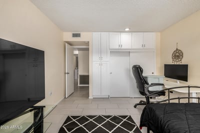 Flexible bedroom offering dedicated workspace potential, built-in storage, tile flooring, and ample room for guests or remote work.