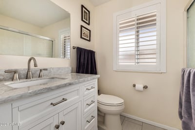 Updated guest bathroom featuring a modern vanity, marble-look countertop, plantation shutters, and quality finishes that complement the home's recent updates.