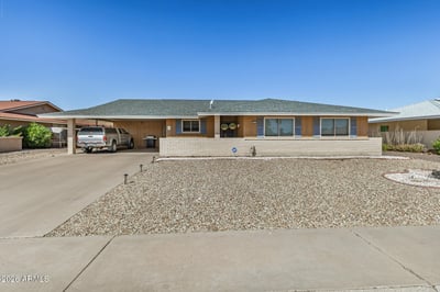 Front exterior features classic architecture, decorative shutters, desert landscaping, and a covered front patio. This Sun City residence combines comfort, curb appeal, and low-maintenance living.