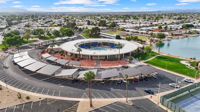 Aerial view highlights the impressive Sun City recreation center with community pool, landscaped grounds, walking paths, and gathering spaces conveniently located nearby.