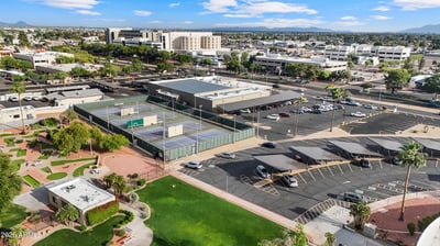 Elevated aerial view features nearby tennis courts, recreation buildings, landscaped green spaces, and convenient neighborhood amenities, showcasing the outstanding lifestyle available in Sun City.