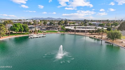 Wide aerial view showcases the community lake, decorative fountain, recreation center, marina, and surrounding neighborhood. Experience the scenic lifestyle available in Sun City.