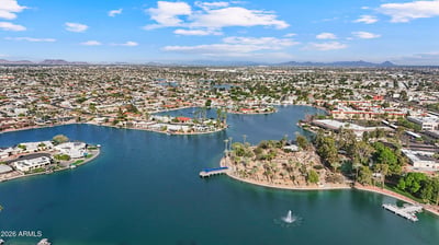Expansive aerial showcases the nearby lake, waterfront homes, mature landscaping, and inviting neighborhood surroundings. Enjoy the scenic beauty that makes Sun City a desirable place to call home.