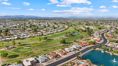 Sweeping aerial view highlights the nearby golf course, fairways, greens, and surrounding neighborhood. Enjoy easy access to premier golf and beautiful outdoor scenery in Sun City.