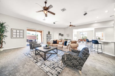 Spacious living area with seamless flow to the kitchen and covered patio, creating an ideal environment for indoor-outdoor entertaining. Large windows and high ceilings provide a bright, airy atmosphere.