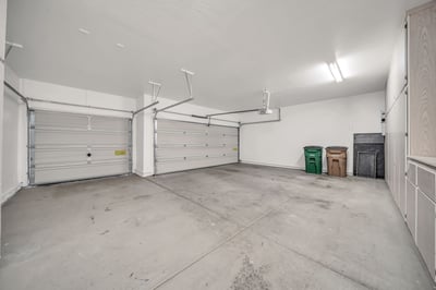 Spacious garage featuring custom cabinets, overhead lighting, and room for vehicles, tools, and recreational equipment. A practical addition to this energy-efficient Palm Valley home.