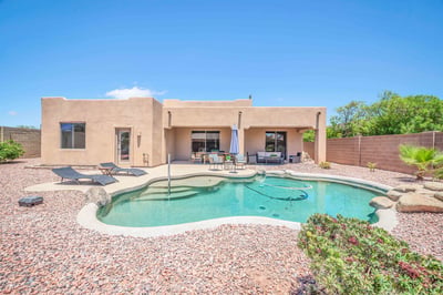 Rear exterior view highlighting the covered patio, refreshing PebbleTec pool, custom waterfall, and low-maintenance landscaping. This inviting backyard completes the exceptional indoor-outdoor lifestyle offered by this Goodyear home.