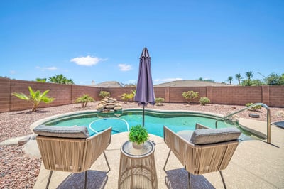 Inviting poolside sitting area offers relaxing views of the sparkling PebbleTec pool and waterfall feature. This thoughtfully designed backyard creates the perfect setting for quiet mornings or gathering with friends.