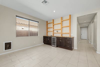 Versatile room with custom built-ins, beverage refrigerator, generous storage, and decorative shelving. Perfect for entertaining, displaying collectibles, or creating a stylish home workspace.