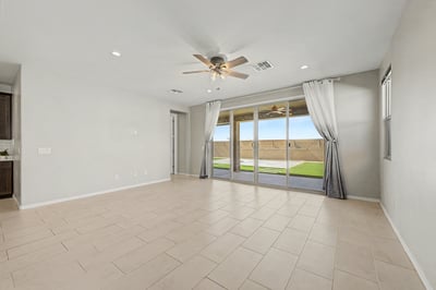 Expansive great room with oversized sliding glass doors, recessed lighting, and durable tile flooring opens to the covered patio and low-maintenance backyard, creating a seamless indoor-outdoor living experience.
