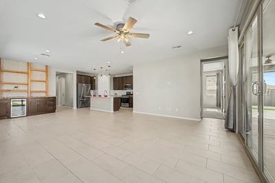 Open-concept living area featuring durable tile flooring, abundant natural light, custom built-in cabinetry with beverage refrigerator, and seamless flow into the gourmet kitchen. Perfect for entertaining and everyday living.