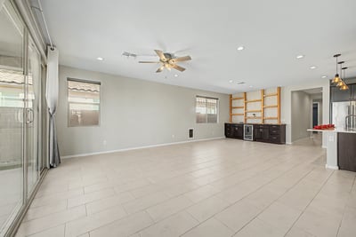Spacious great room with recessed lighting, ceiling fan, and oversized sliding glass doors that connect indoor and outdoor living. The custom built-in entertainment area adds both style and functionality.