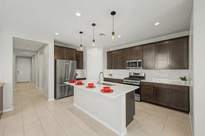 Modern kitchen featuring quartz countertops, a large center island, stainless steel appliances, subway tile backsplash, and extensive cabinetry. Designed for cooking, entertaining, and gathering with family and friends.