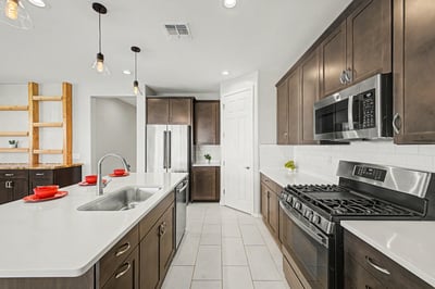Stylish kitchen featuring a stainless steel gas range, built-in microwave, quartz countertops, oversized island, and generous storage. Modern finishes and thoughtful design create a beautiful and functional workspace.