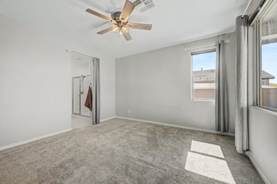 Comfortable primary suite featuring plush carpeting, large windows, ceiling fan, and private access to the ensuite bathroom. A relaxing retreat designed for rest and everyday comfort.