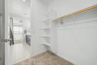 Spacious walk-in closet featuring built-in shelving, dedicated hanging space, and direct access to the primary bathroom. Designed to maximize storage while keeping everyday essentials organized.