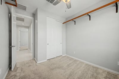 Spacious guest bedroom featuring soft carpeting, ceiling fan, generous closet, and neutral finishes. A welcoming space offering flexibility for family, visitors, or remote work.