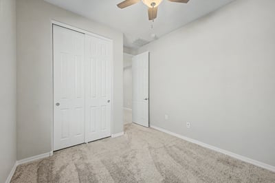 Well-sized bedroom featuring a large closet, soft carpeting, ceiling fan, and bright window. An adaptable room that easily functions as a bedroom, office, or creative workspace.