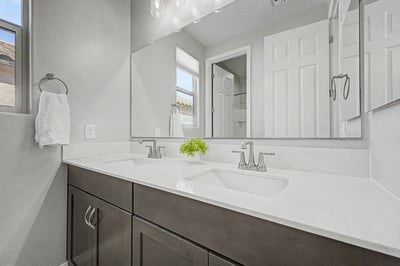 Contemporary bathroom with a quartz double-sink vanity, oversized mirror, modern fixtures, and ample cabinetry. Designed to provide both style and everyday practicality.