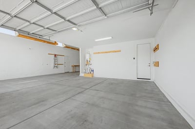 Spacious three-car garage offering extensive storage potential, room for multiple vehicles, overhead lighting, and organized wall-mounted storage. An excellent addition for homeowners seeking flexibility and convenience in Wittman.