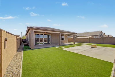 Attractive backyard featuring lush artificial turf, spacious covered patio, and an oversized concrete gathering area with a fire pit. Designed for low-maintenance living and memorable outdoor entertaining.