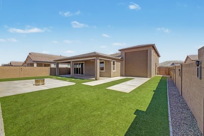 Rear elevation showcasing the covered patio, oversized RV garage, low-maintenance artificial turf, and expansive outdoor living spaces. A backyard designed to maximize comfort and functionality.
