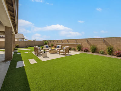 Virtually Staged Beautifully landscaped backyard with premium artificial turf, expansive patio space, decorative stepping stones, and a covered outdoor living area. A perfect setting for relaxing, entertaining, and enjoying the Arizona lifestyle in Wittman.