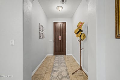 The welcoming foyer features elegant tile flooring, neutral finishes, and a beautiful wood entry door that sets the tone for this move-in-ready home with thoughtful design throughout.
