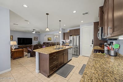 Designed for everyday living and entertaining, this gourmet kitchen features granite countertops, stainless steel appliances, a spacious island, abundant cabinetry, and a walk-in pantry with plenty of storage.