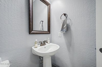 This beautifully maintained powder room offers a pedestal sink, framed mirror, and contemporary fixtures, providing guests with comfort and convenience while complementing the home's elegant finishes.