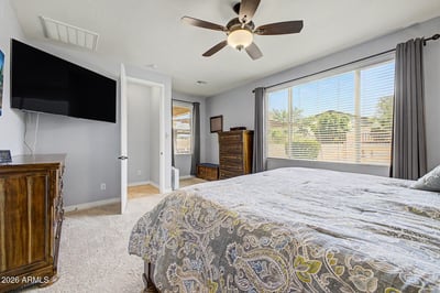 Oversized windows fill the owner's bedroom with natural light while plush carpet, ceiling fan, and generous proportions provide everyday comfort in this beautiful rental home in Goodyear.