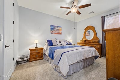 This spacious guest bedroom offers soft carpeting, ceiling fan, and room for comfortable furnishings, creating an inviting space for family or overnight guests in Goodyear.