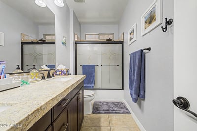 Granite countertops, modern cabinetry, tile flooring, and a full shower/tub combination create a clean and welcoming guest bathroom in this Goodyear rental property.