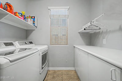 Complete with storage cabinets, countertop workspace, shelving, and space for full-size laundry appliances, this functional laundry room adds convenience to everyday living in Goodyear.