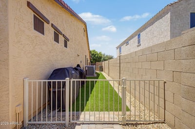 The secure side yard features artificial turf, gated access, and low-maintenance landscaping, providing extra flexibility for outdoor living and storage in this Goodyear property.
