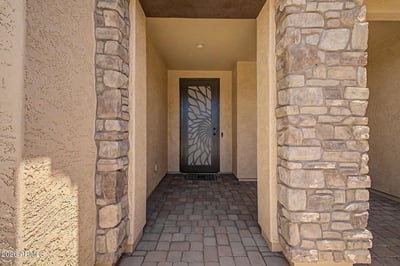 The welcoming front entrance features decorative stone columns, elegant paver flooring, and a custom security door that enhances both style and everyday functionality in this Goodyear rental.