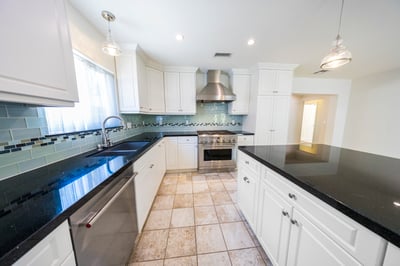 Large chef's kitchen with granite countertops, glass tile surround