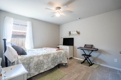 Cozy bedroom featuring natural light, a ceiling fan, and space for personal touches and creativity.