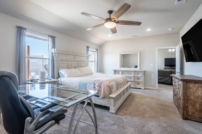 Bright and spacious bedroom featuring modern furnishings, ample natural light, and a convenient workspace.