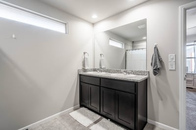 Modern bathroom featuring a double vanity with granite countertops and abundant natural light.