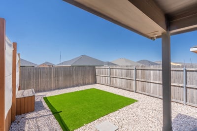 Bright, low-maintenance backyard featuring artificial turf and gravel, perfect for outdoor gatherings and relaxation.