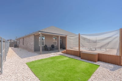 This contemporary home features a spacious yard with synthetic grass and a private outdoor seating area.