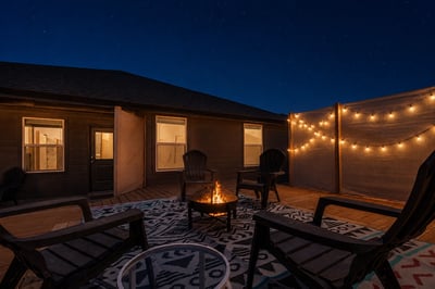 Cozy outdoor space featuring a fire pit, string lights, and comfortable seating for evenings under the stars.
